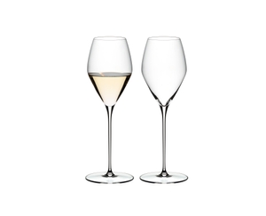 Two RIEDEL Veloce Sauvignon Blanc glasses one filled with white wine and one unfilled on a white background.