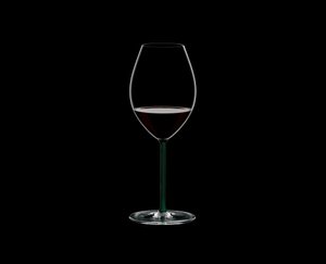 RIEDEL Fatto A Mano Syrah Green filled with a drink on a black background