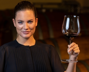A RIEDEL Superleggero Burgundy Grand Cru glass filled with red wine on a white background.