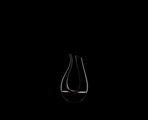 RIEDEL Decanter Black Tie Amadeo R.Q. filled with a drink on a black background
