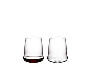 Two SL RIEDEL Stemless Wings Cabernet Sauvignon tumblers side by side on a white background. The glass on the right side is filled with red wine, the other one is empty.