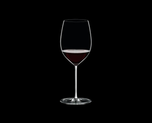 RIEDEL Fatto A Mano Cabernet/Merlot White filled with a drink on a black background