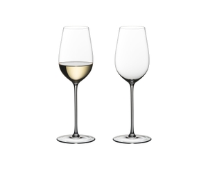 Two RIEDEL Superleggero Riesling/Zinfandel glasses stand side by side on white background. The glass on the left side is filled with white wine, the other one is empty.