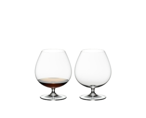 2 RIEDEL Vinum Brandy glasses standing side by side. One is filled with Brandy, the other glass is empty.
