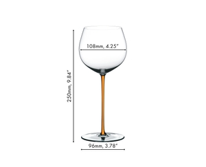 A RIEDEL Fatto A Mano Oaked Chardonnay glass in orange filled with white wine on a white background. 