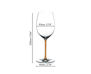 A RIEDEL Fatto A Mano Cabernet with an orange stem and filled with red wine on a white background.