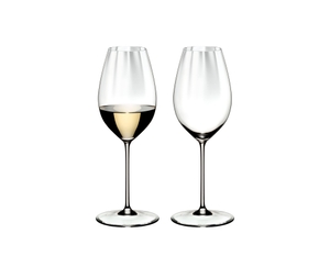 Two RIEDEL Perfromance Sauvignon Blanc glasses one filled with white wine and one unfilled on a white background.