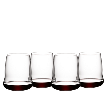 Four SL RIEDEL Stemless Wings Cabernet/Merlot glasses filled with red wine stand side by side or slightly behind each other on a white background.