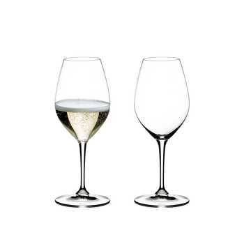2 RIEDEL Vinum Champagne Wine Glasses standing side by side. The glass on the left side is filled with Champagne, the other one is empty.