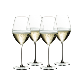 Four filled RIEDEL Veritas Champagne Wine glasses stand slightly offset next to each other