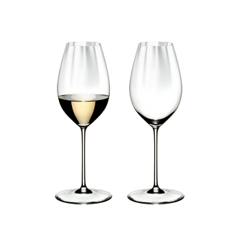 Two RIEDEL Perfromance Sauvignon Blanc glasses one filled with white wine and one unfilled on a white background.