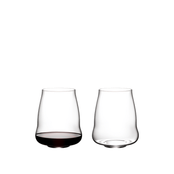 Two SL RIEDEL Stemless Wings Pinot Noir/Nebbiolo glasses on a white background. The SL RIEDEL Stemless Wings Pinot Noir/Nebbiolo glass on the left side is filled with red wine, the other one is unfilled.