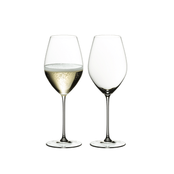 Two RIEDEL Veritas Champagne Wine Glasses one filled with champagne and one unfilled on a white background.