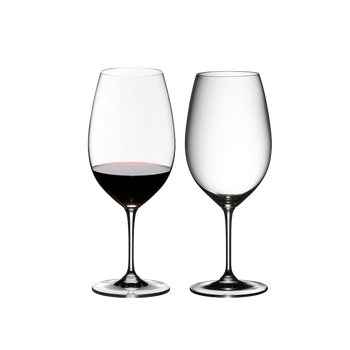 Two RIEDEL Vinum Syrah/Shiraz/Tempranillo glasses side by side. The glass on the left side is filled with red wine, the other one is empty.