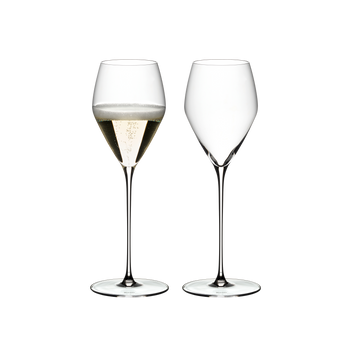 Two RIEDEL Veloce Champagne Wine Glasses one filled with champagne and an unfilled glass on a white background.