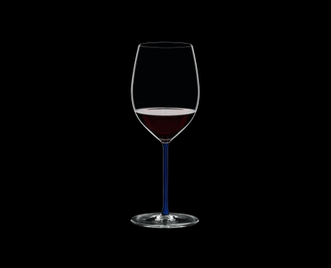 RIEDEL Fatto A Mano Cabernet/Merlot Dark Blue filled with a drink on a black background