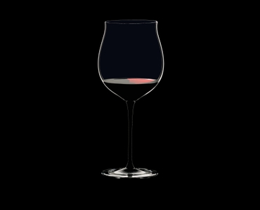 RIEDEL Sommeliers Black Tie Burgundy Grand Cru filled with a drink on a black background