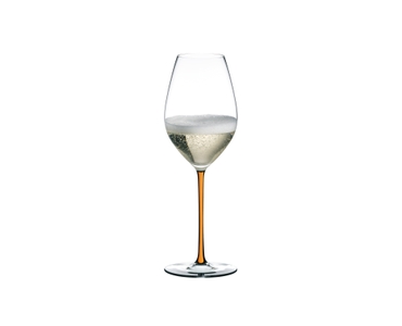 A RIEDEL Fatto A Mano Champagne Glass with an orange stem and filled with champagne.