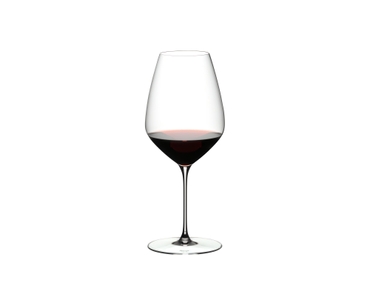 Two RIEDEL Veloce Syrah/Shiraz glasses one filled with red wine and one unfilled on a white background.