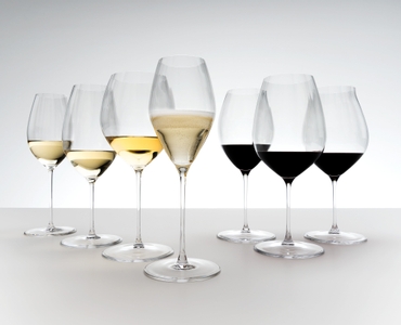 A RIEDEL Performance Riesling glass filled with white wine on white background.