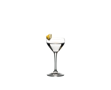 A RIEDEL Drink Specific Glassware Nick & Nora glass filled with a Martini is standing on a black table in front of a background.