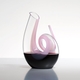 A RIEDEL Decanter Curly Pink filled with red wine on white background.