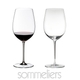 Two RIEDEL Sommeliers Bordeaux Grand Cru glasses on white background. The one on the left side is filled with red wine, the other one is empty.