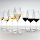 A RIEDEL Performance Riesling glass filled with white wine on white background.