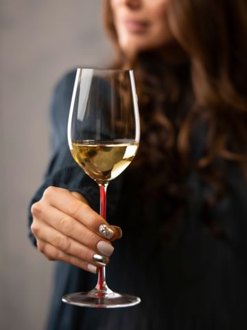 woman holding white wine glass
