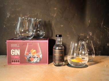 RIEDEL Gin Set X Four Pillars Rare Dry Gin with packaging on a marble bench top with a black background.