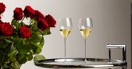 two champagne wine glasses on a tray next to roses