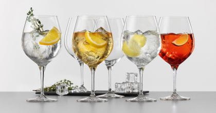 Quatre verres SPIEGELAU Vino Grande remplis de différents cocktails Gin et Tonic. En arrière-plan, deux verres à Gin et Tonic vides et un plateau de service avec des glaçons et du thym.<br/>