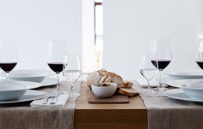 The filled SPIEGELAU Vino Grande Bordeaux glass and Mineral Water Glass on a laid table. On the plates there are matching soup plates and besides them is cutlery and bread.<br/>