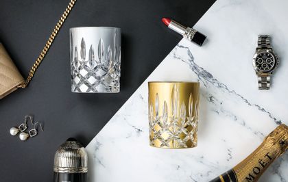 RIEDEL Laudon Silver and Gold on a black and white marble background with jewellery, makeup and a purse scattered around them.