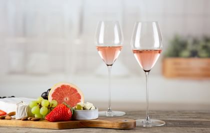 two rose glasses next to food platter