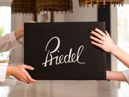 Two sets of hands holding up a black RIEDEL box.