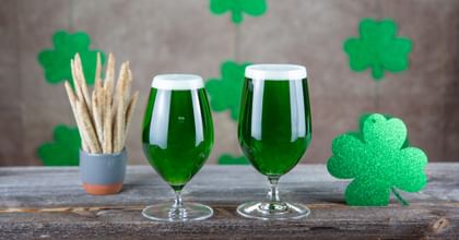  RIEDEL Beer glasses filled with green beer on a table with a fourclover as decoration