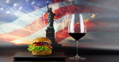 hamburger next to red wine glass in front of American flag