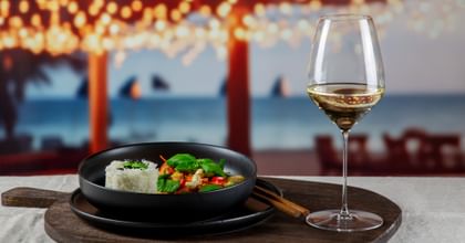 RIEDEL wine glass next to a Thai curry dish