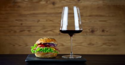 hamburger next to red wine in glass