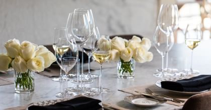 Various wine glasses on set table with white roses