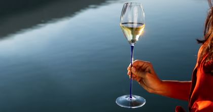 hand holding RIEDEL white wine glass near water