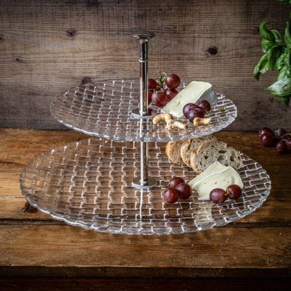 The NACHTMANN Bossa Nova crystal two tier tray with grapes, cheese, nuts and slices of bread on it.<br/>