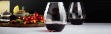 two red wine glasses next to tomatoes