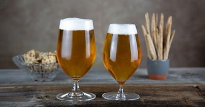 two different Riedel Beer glasses, RIEDEL Bar Beer & RIEDEL Veritas Beer filled with beer on a wooden table