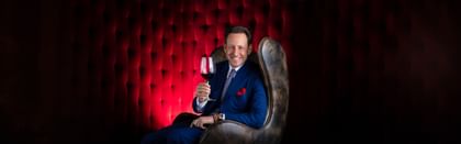 Maximilian J. Riedel sitting holding a glass of wine
