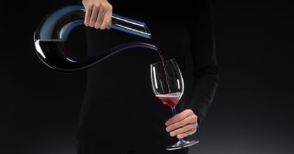 hands pouring wine from a decanter into a glass