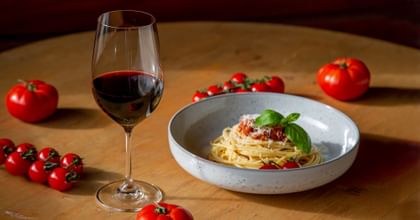 RIEDEL red whine glass next to a bowl of pasta