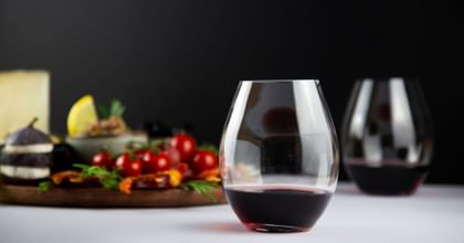 stemless red wine glasses next to vegetable dish