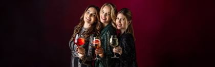 three women smiling with various cocktails in GRAPE@RIEDEL glasses